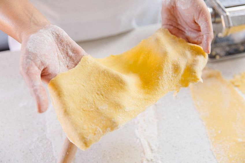 Des mains tenant un morceau de pâte, saupoudrée de farine, dans une cuisine. 1