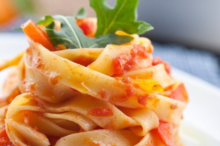 A close-up of a pasta dish with a tomato-based sauce, garnished with a leaf. 2