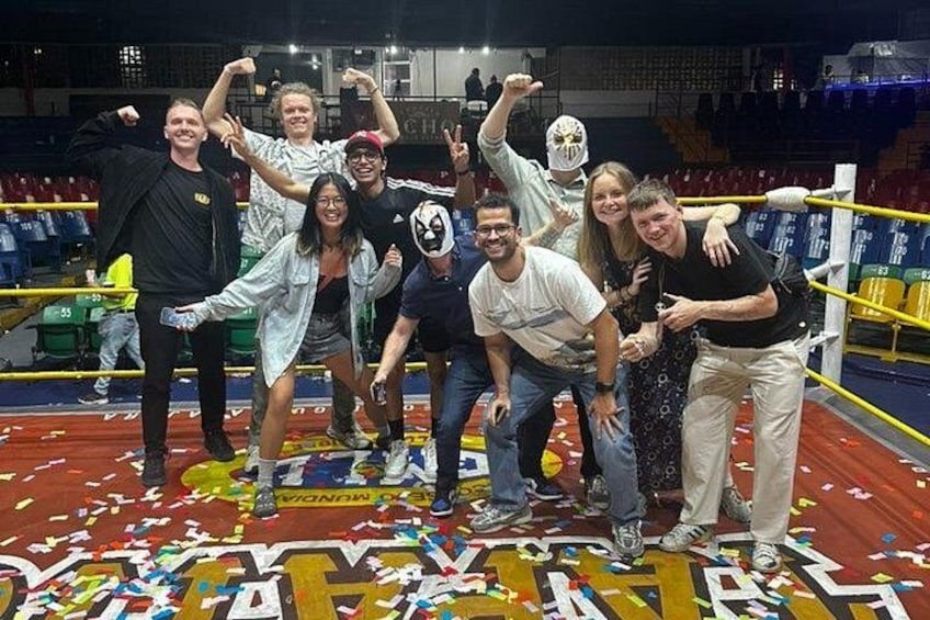 Un grupo de personas posando en un ring de boxeo con confeti en el suelo. 3