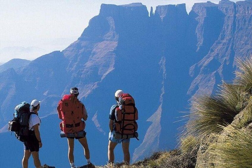 Four hikers on a mountain trail with a canyon in the background. 4