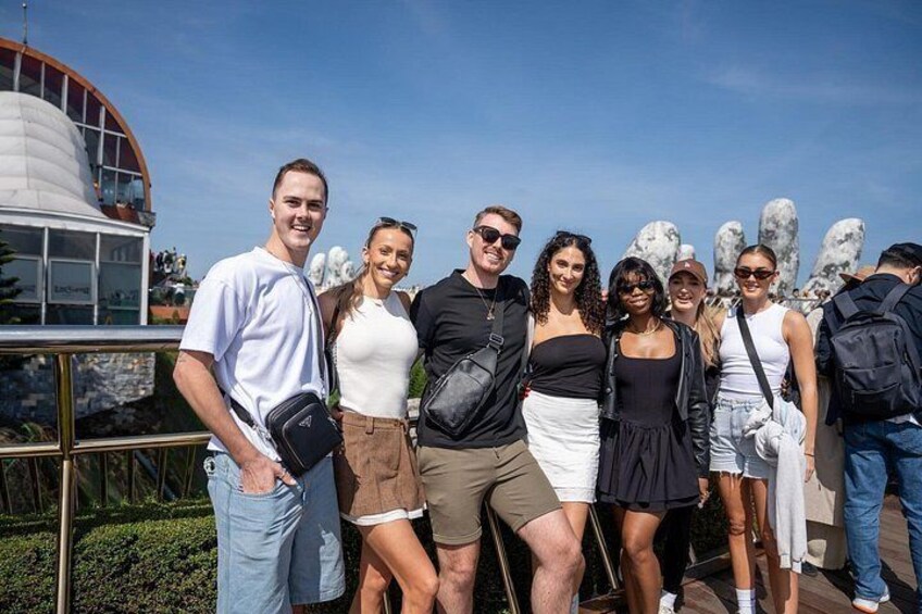 A group of people posing in front of a building with a dome and a sculpture garden. 5