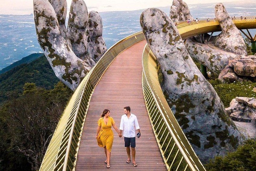 A couple walking on a wooden bridge with large rock formations on either side. 2
