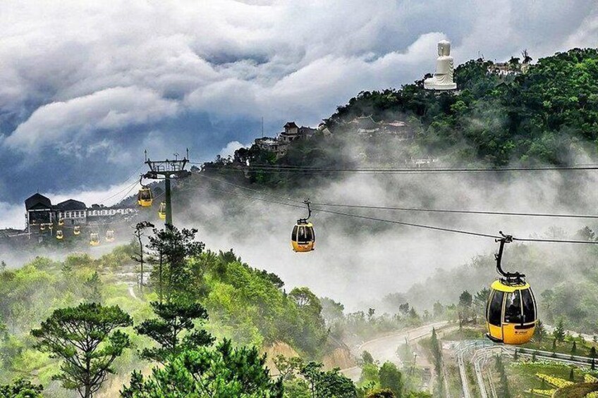 A cable car system with cabins, a mountain landscape, and a large white statue. 2