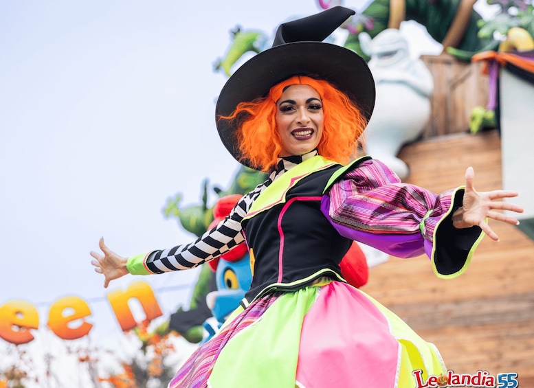 A person in a colorful costume with a large hat, standing in front of a sign with the word 'green' visible. 4