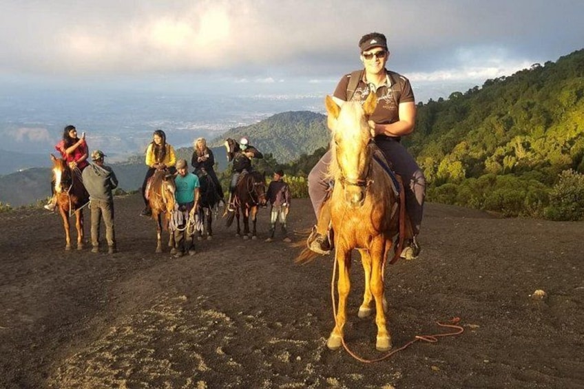 A group of people on horseback on a dirt path with a mountainous landscape in the background. 3