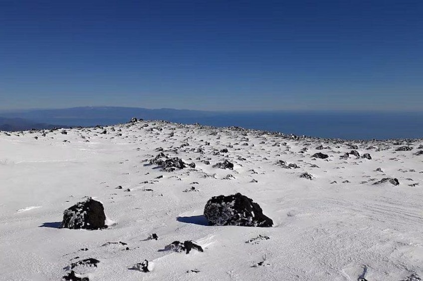 Un paisaje nevado con rocas dispersas y un cielo azul despejado. 2