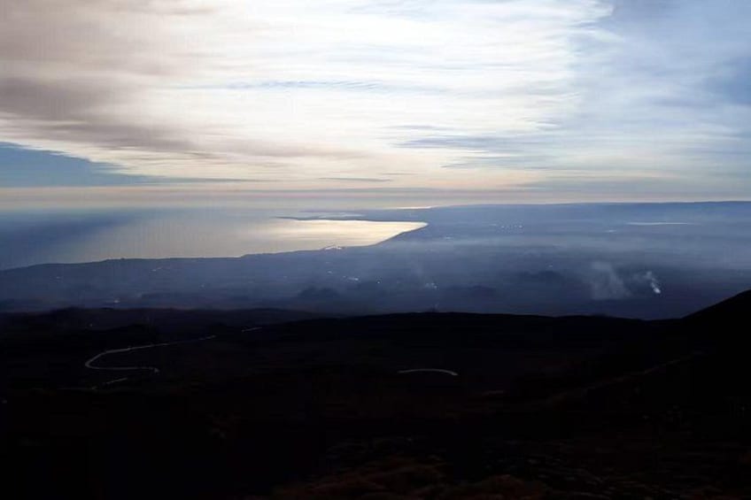 Un paisaje montañoso con un camino serpenteante y una masa de agua en la distancia. 4