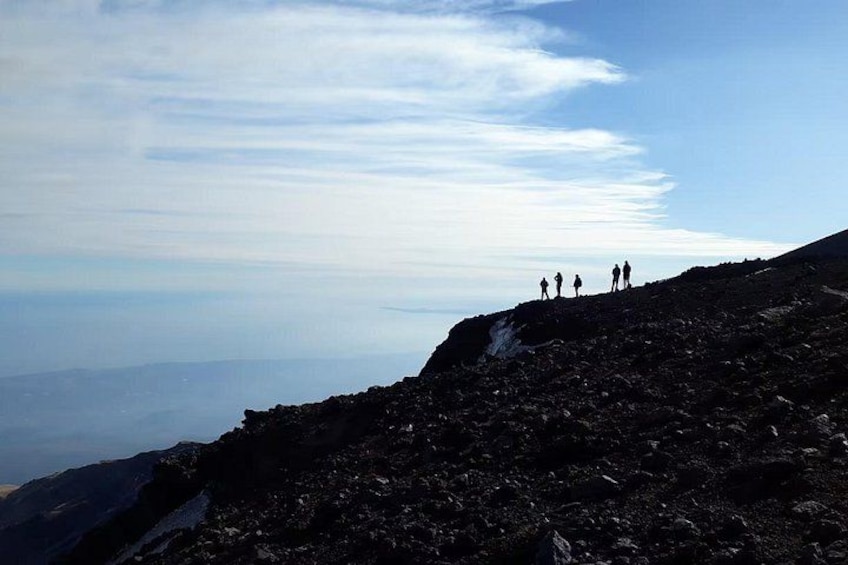 Pendiente rocosa de una montaña con algunas personas al borde. 3