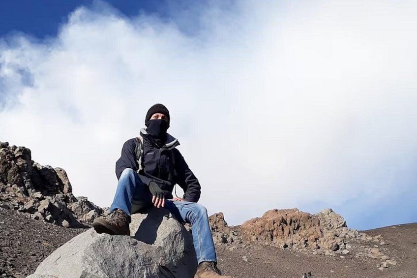 Una persona sentada sobre una roca, con un paisaje montañoso al fondo. 5