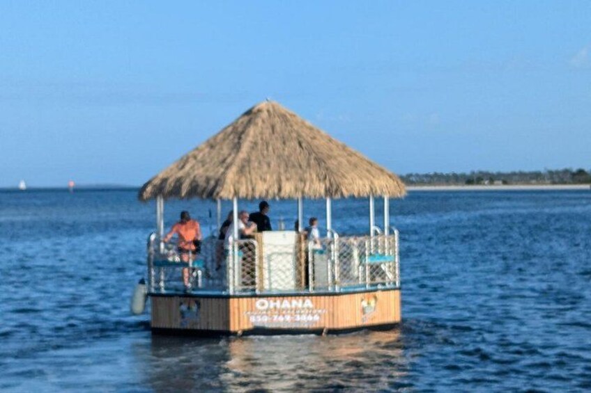 A boat with a thatched roof and people on it, floating on calm water. 2