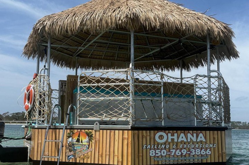 A wooden boat with a thatched roof, labeled 'OHANA Sailing & Excursions,' docked at a marina. 3