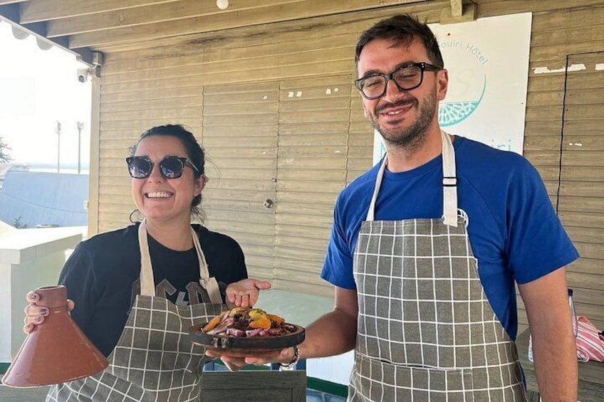 Dos personas con delantales, una sosteniendo una maceta de terracota y la otra una fuente con comida. 3