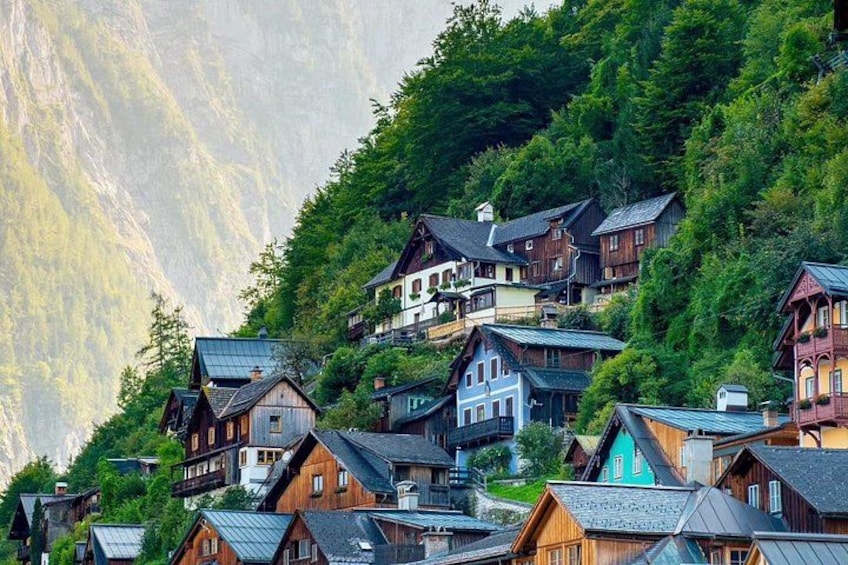 Eine Gruppe traditioneller Holzhäuser an einem Hang mit einem Berg im Hintergrund. 2