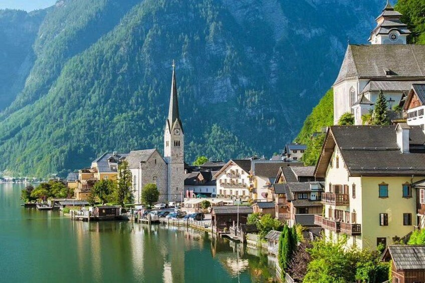 Ein Dorf am See mit einer Kirche, Häusern und Bergen im Hintergrund. 4