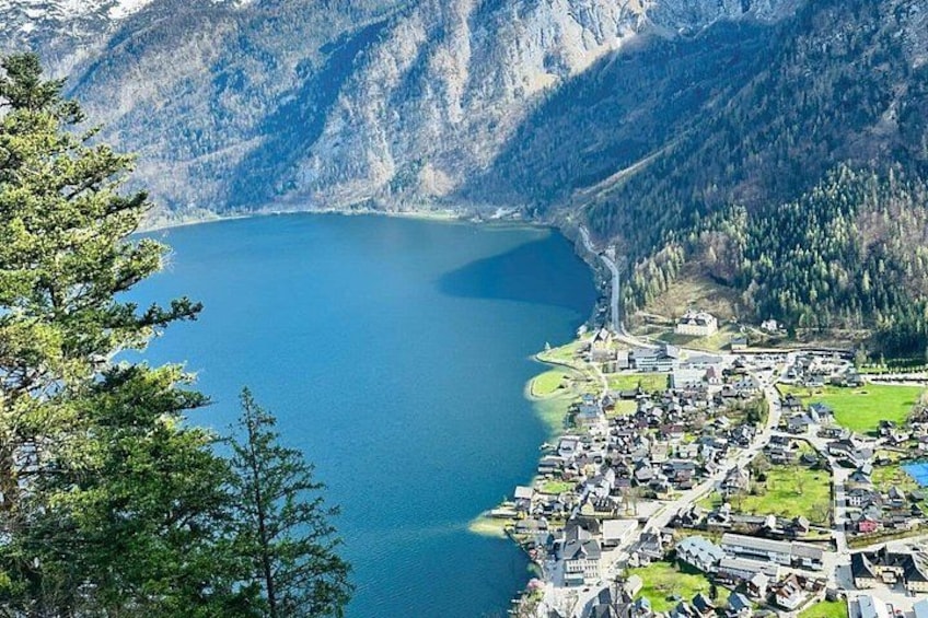 Ein See, umgeben von Bergen, eine kleine Stadt mit Gebäuden und dichter Wald. 5