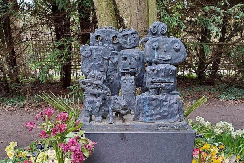 Una escultura de piedra con diferentes rostros en un jardín. 3