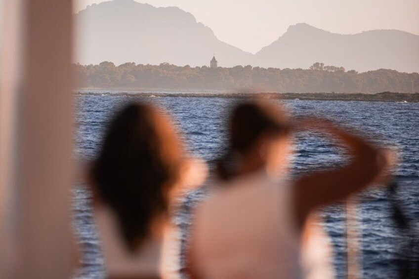 Two people looking out at a body of water with mountains in the background. 3