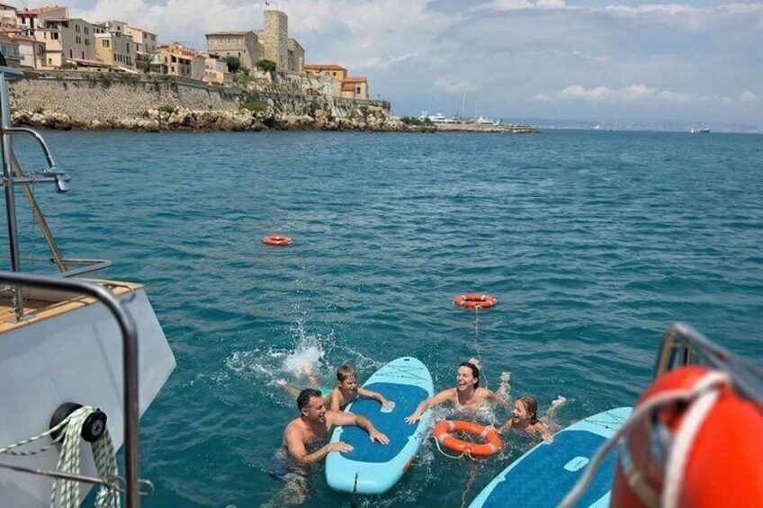Persone su imbarcazioni con cerchi gonfiabili, una costa rocciosa e un cielo sereno. 1