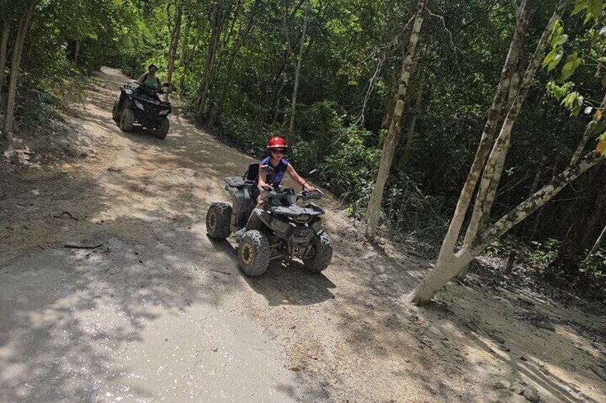 Two people riding ATVs on a dirt path in a forest. 5