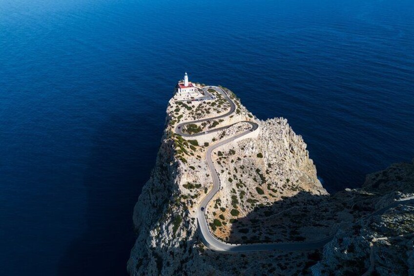 A coastal cliff with a winding road and a lighthouse. 2