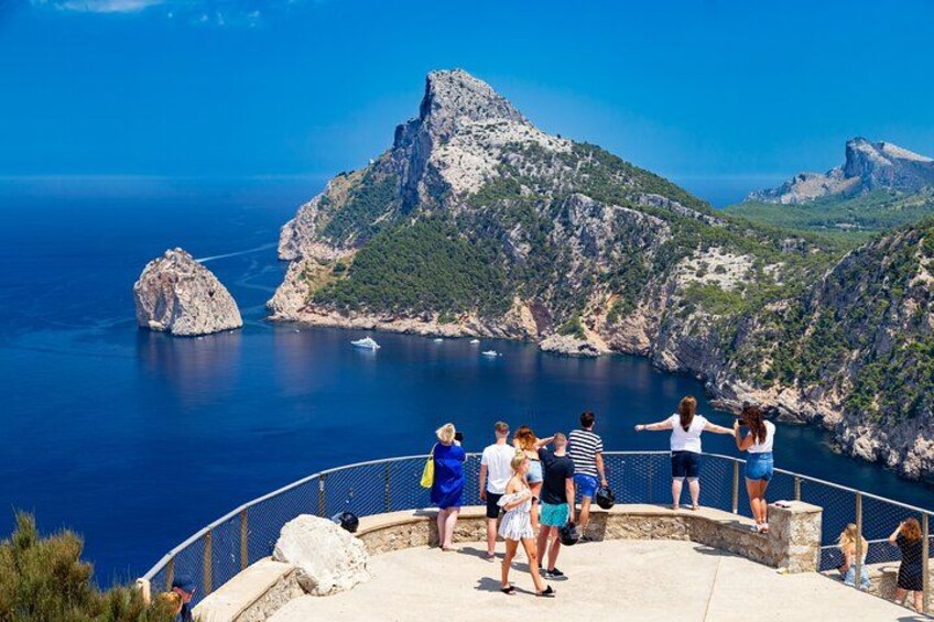 A group of people on a coastal overlook with a view of rocky cliffs and the sea. 3