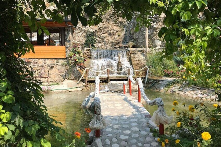 A stone bridge over a small pond with a waterfall in the background. 4