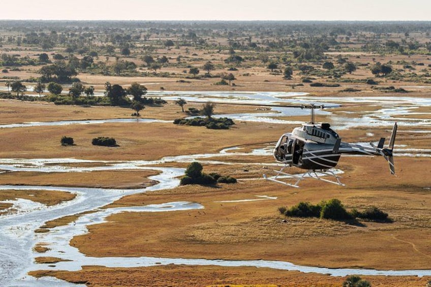 Un hélicoptère survole un lit de rivière asséché, où la végétation est clairsemée. 4