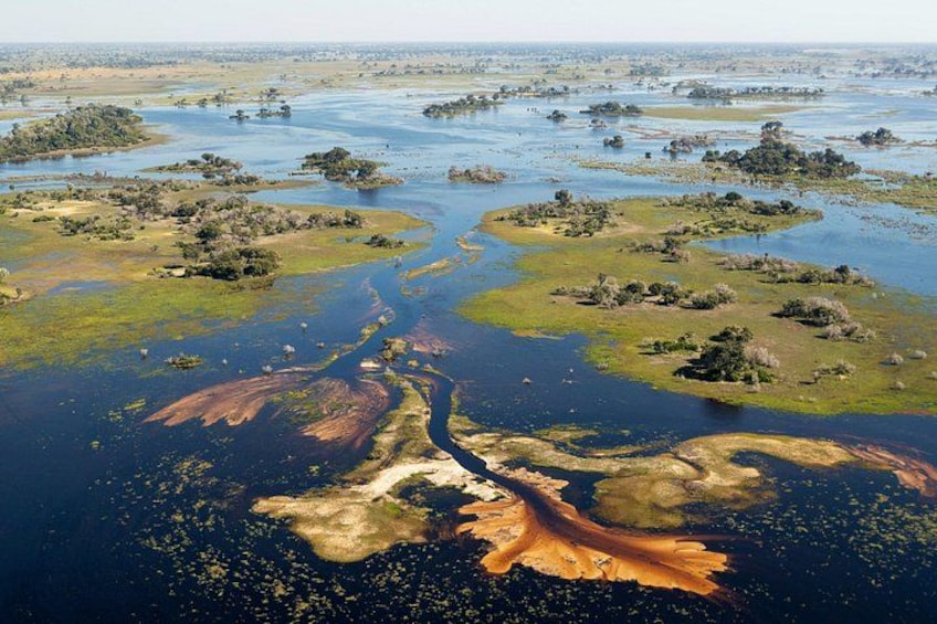 Une rivière serpente à travers un paysage parsemé de zones verdoyantes et de plans d’eau. 3