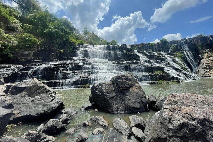 Ein mehrstufiger Wasserfall, umgeben von Felsen und Grünpflanzen. 4