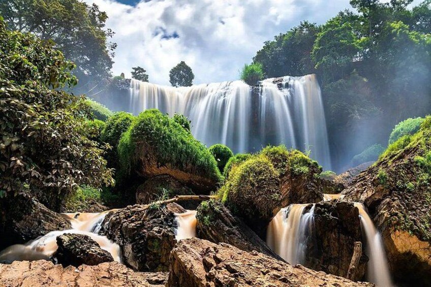 Ein Wasserfall, umgeben von üppiger Vegetation und felsigem Gelände. 3