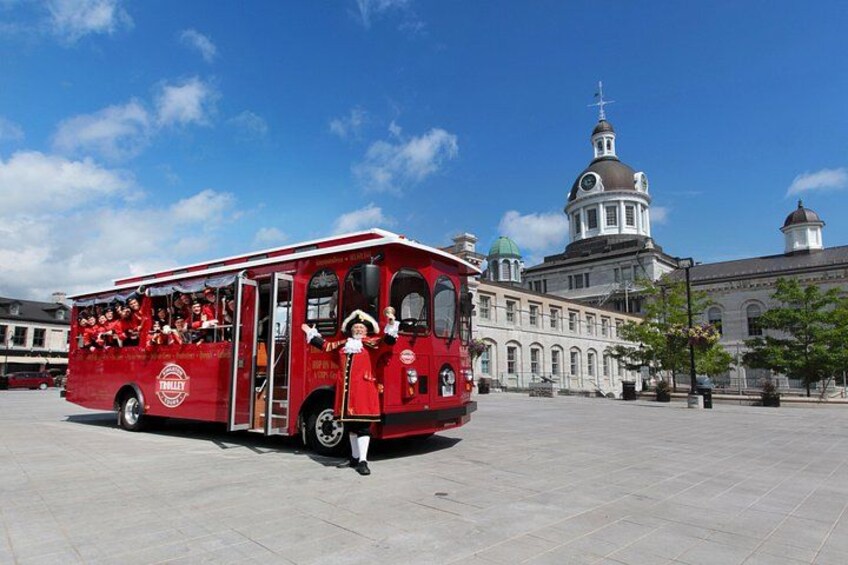 A red bus with passengers, a large building with a dome, and a clear blue sky. 1