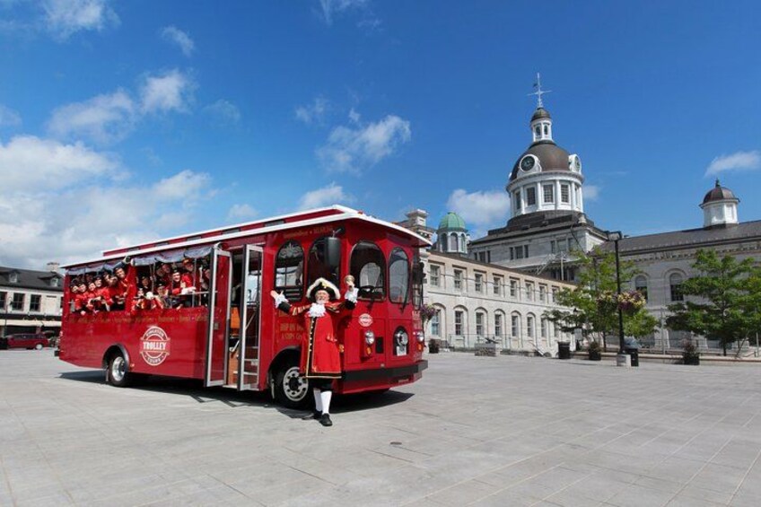 A red bus with passengers, parked in front of a historic building with domes. 1