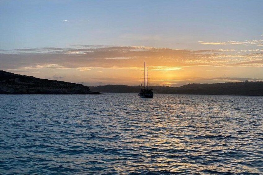 A sailboat on calm water during sunset with a hilly landscape in the background. 5