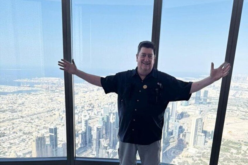 A person standing inside a skyscraper with arms outstretched, overlooking a cityscape. 4
