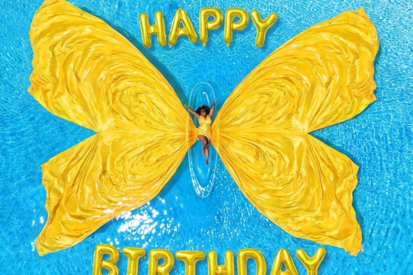 A person in a pool with yellow butterfly balloons and the words 'HAPPY BIRTHDAY' written in gold. 5