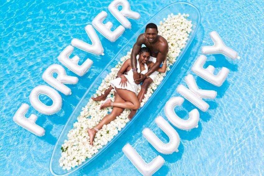 A couple in a pool with inflatable letters spelling 'FOREVER LUCKY'. 4