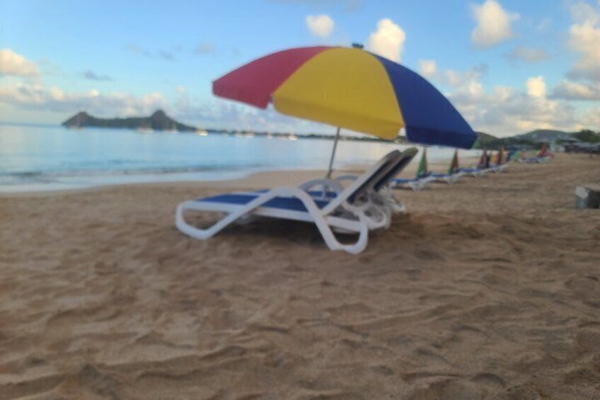 A beach with a lounge chair and a colorful umbrella. 2