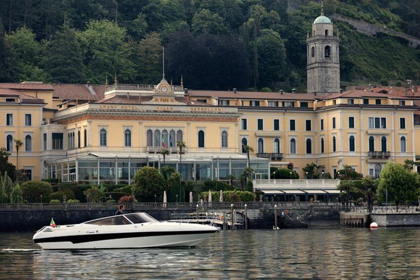 A white yacht docked near a historic building with a tower, surrounded by water and greenery. 4