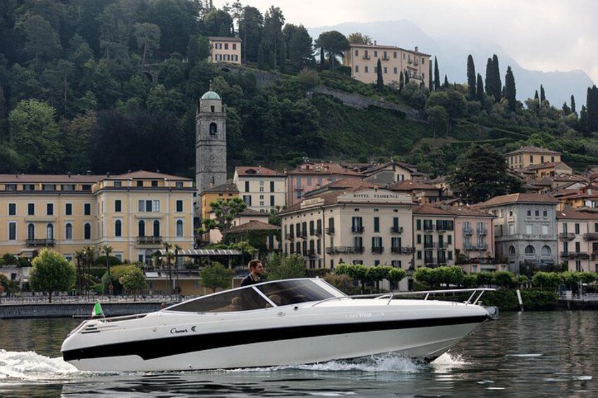A speedboat on water with buildings and a tower in the background. 2