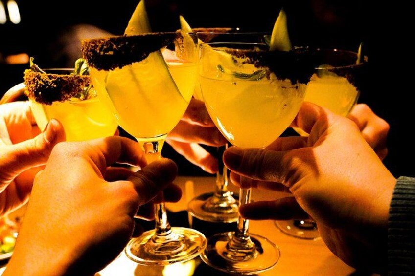 A group of people holding margaritas with lime garnishes. 1