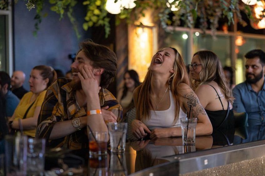 A group of people sitting at a bar with drinks. 1