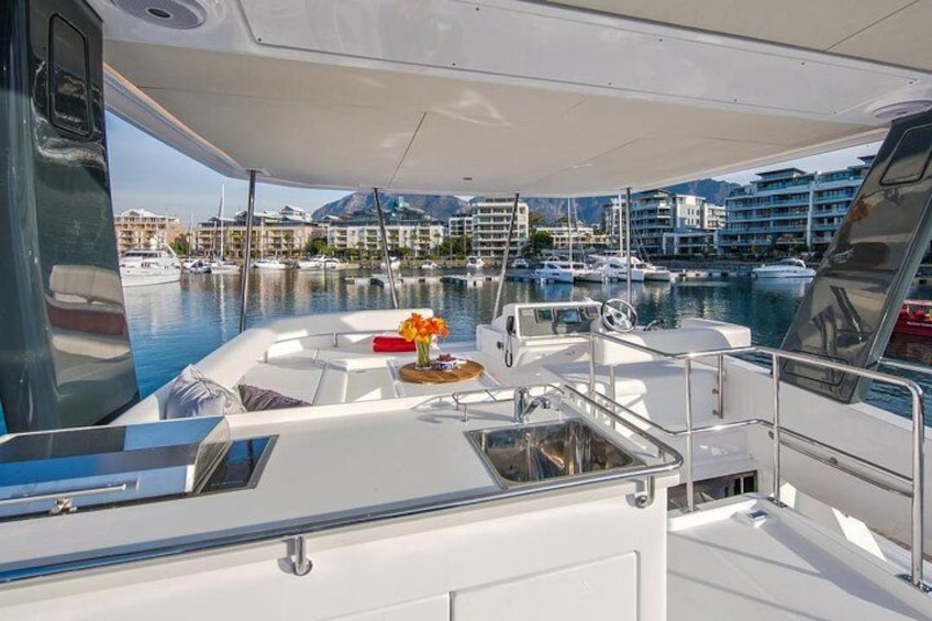 A boat deck with a table, chairs, and a flower arrangement. 2