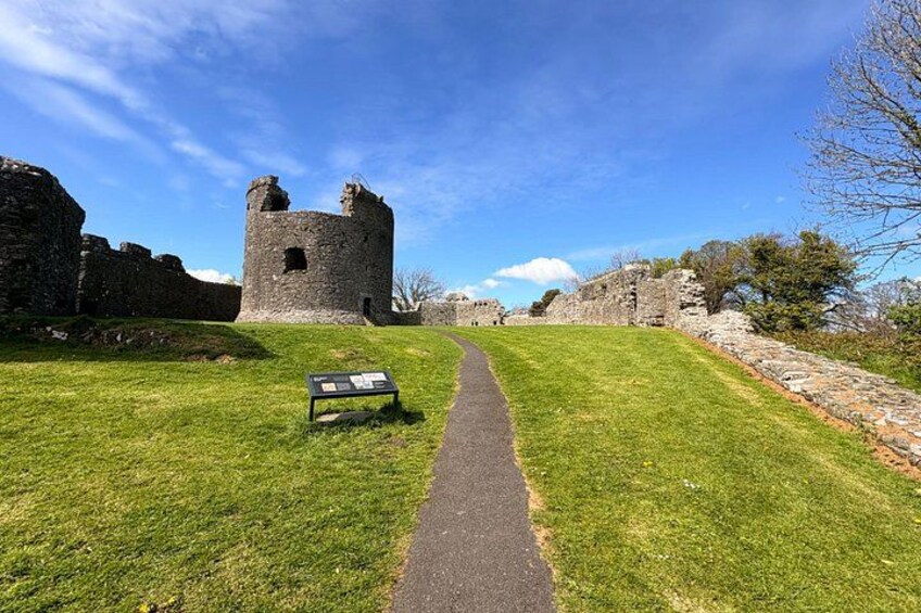 Les ruines d’un château, avec un sentier herbeux menant à l’endroit, un panneau indicateur et un ciel bleu dégagé. 3