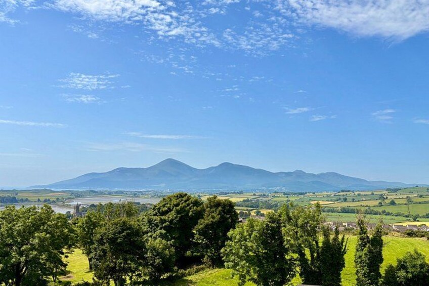 A mountain range, a river, and a green landscape with trees. 1