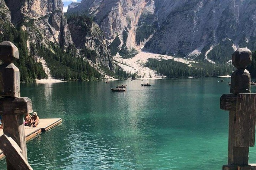 Un lago circondato da montagne, moli di legno e una scultura in legno. 3