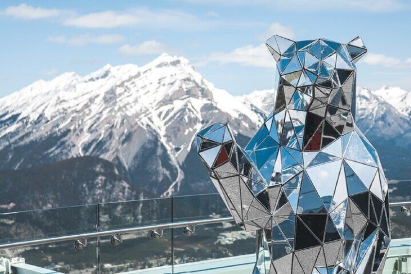 A glass sculpture resembling a bear with a snowy mountain range in the background. 5