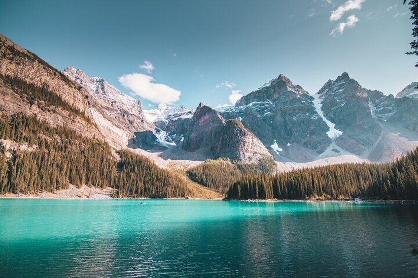 A turquoise lake surrounded by forested mountains with snow-capped peaks. 4