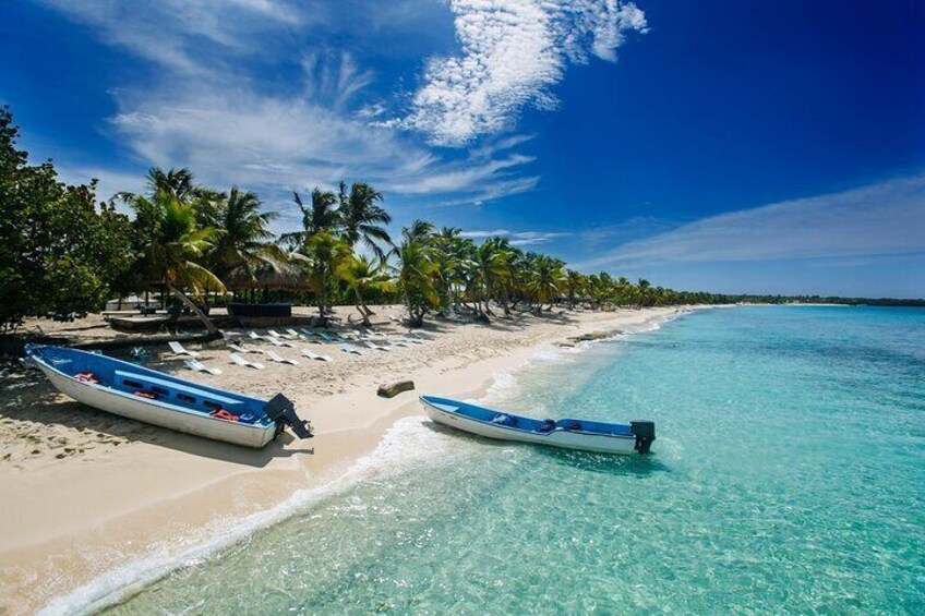 Une plage avec deux bateaux, des palmiers et une eau turquoise cristalline. 2