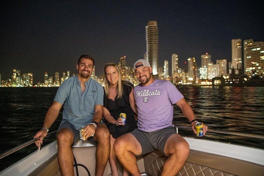 Drie mensen in een boot, met een stadsachtergrond op de achtergrond. 2