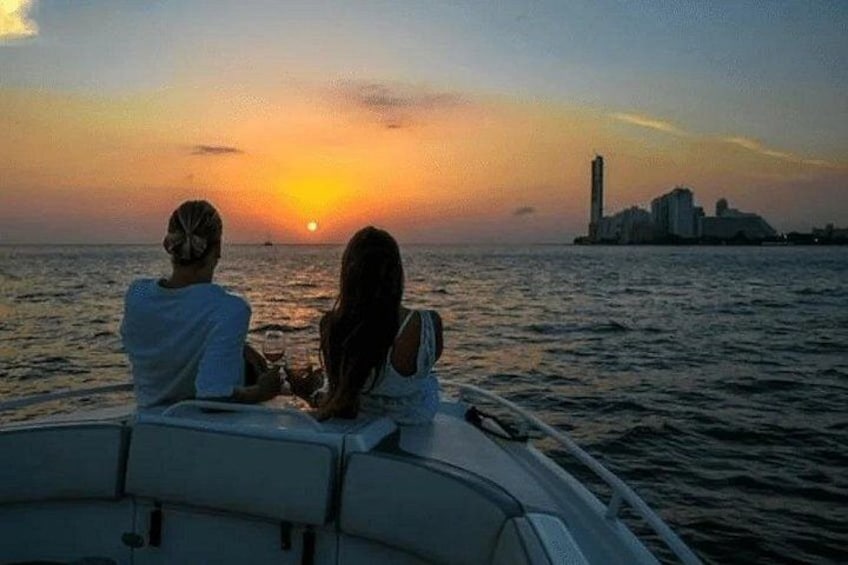 Twee personen in een boot tijdens de zonsondergang, met een stadsachtergrond op de achtergrond. 1